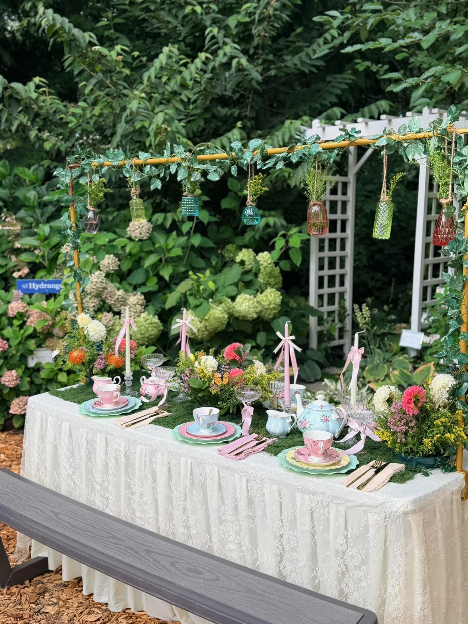 Garden tea table with floral arrangements, pink candles and pastel place settings