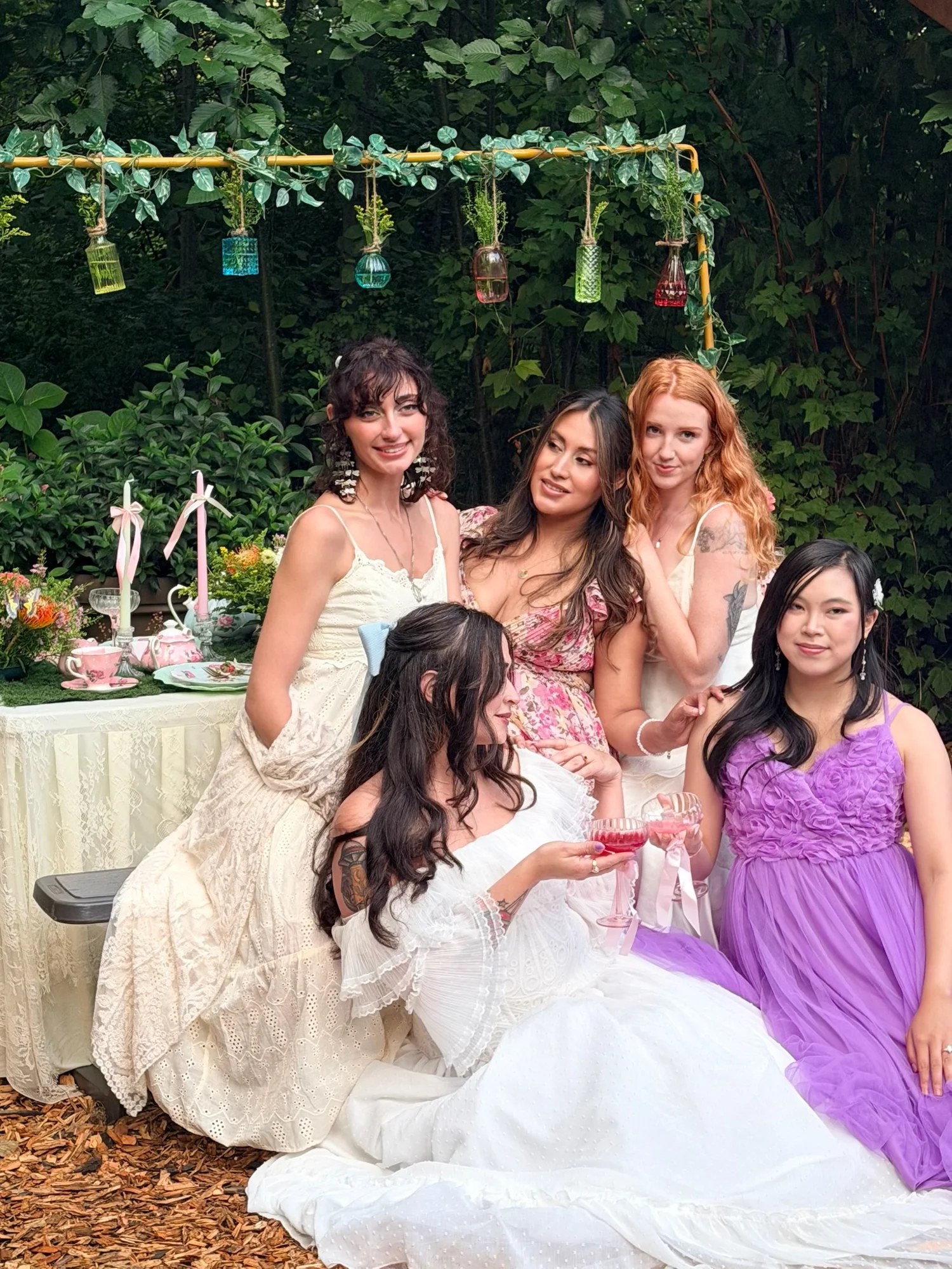 Five guests posing together beside the garden tea table